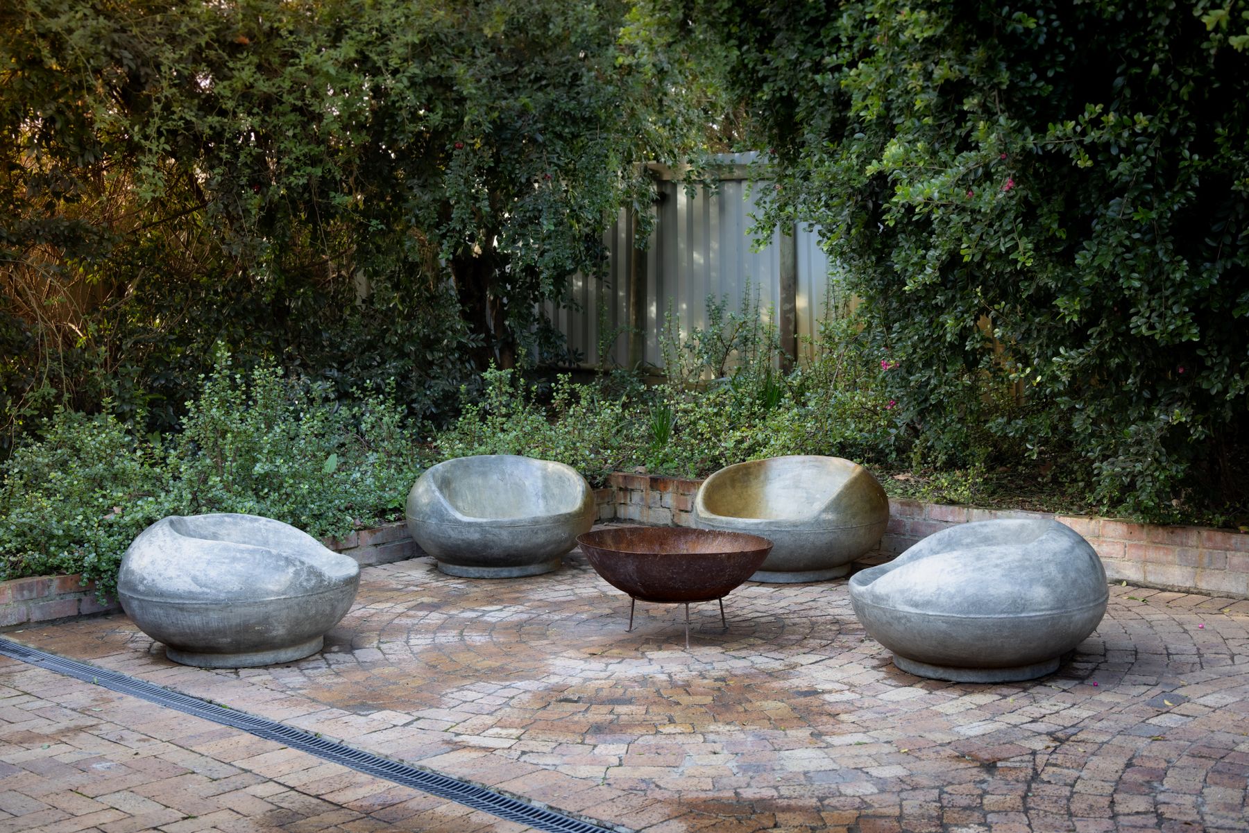 Hardscape inspiration: tan and charcoal paver patio with a fire bowl and sculptural stone seating